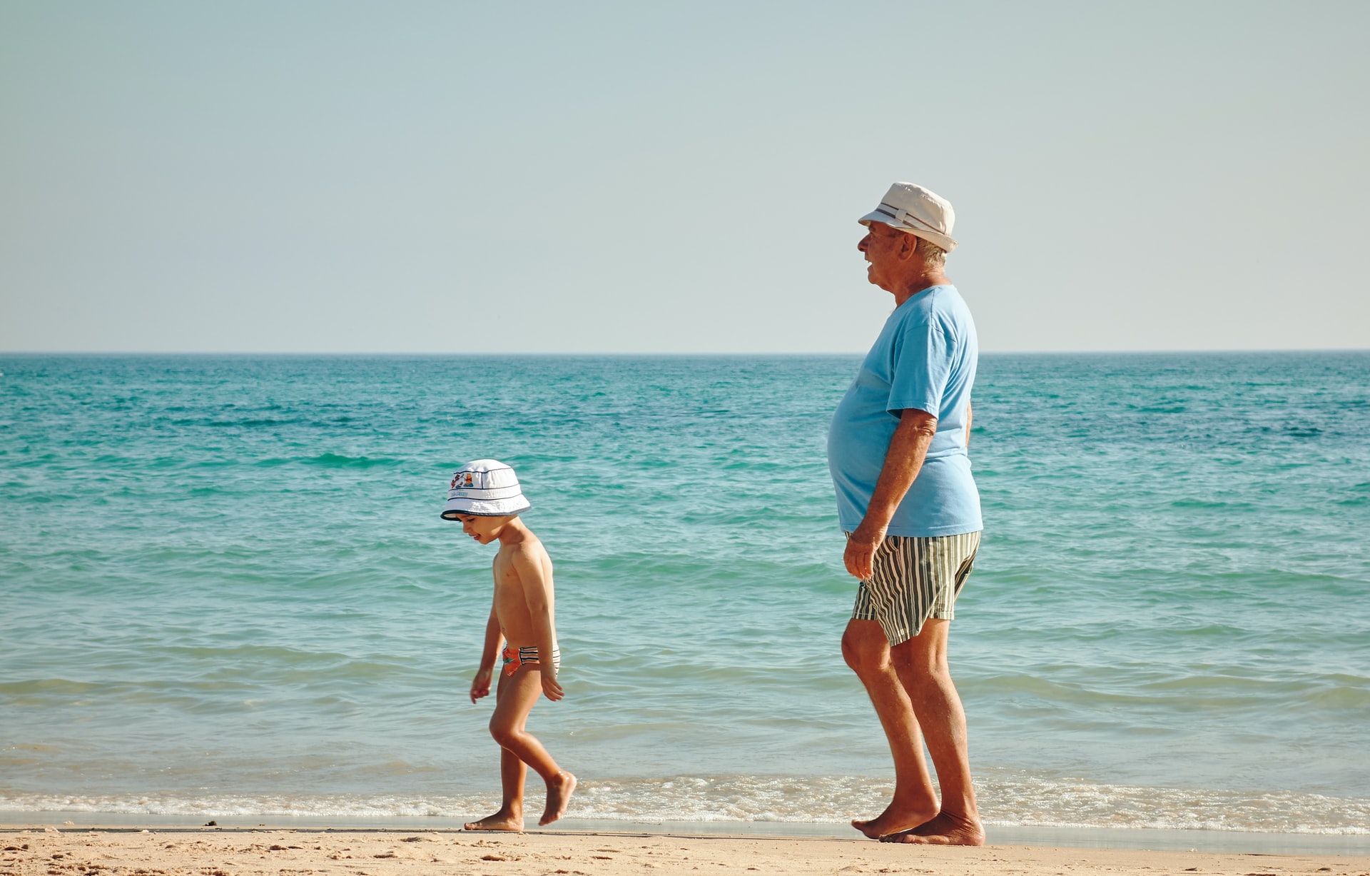 海辺を歩く祖父と孫